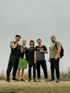 Five people posing together outdoors beneath an overcast sky.