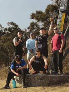 A hiking group gathered beside a stone trail marker.