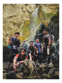 A group gathered beside rocks and a waterfall.