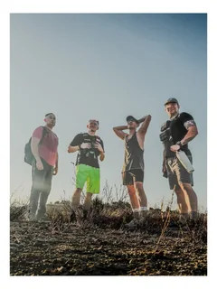 Four hikers standing on a ridge in misty light.