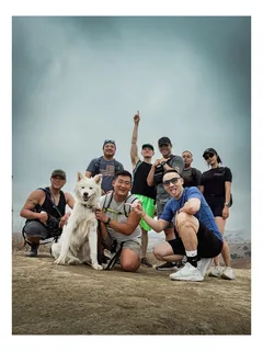 A hiking group and a white dog gathered on a hilltop.