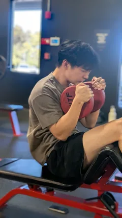 A man performing a weighted crunch on an exercise bench.
